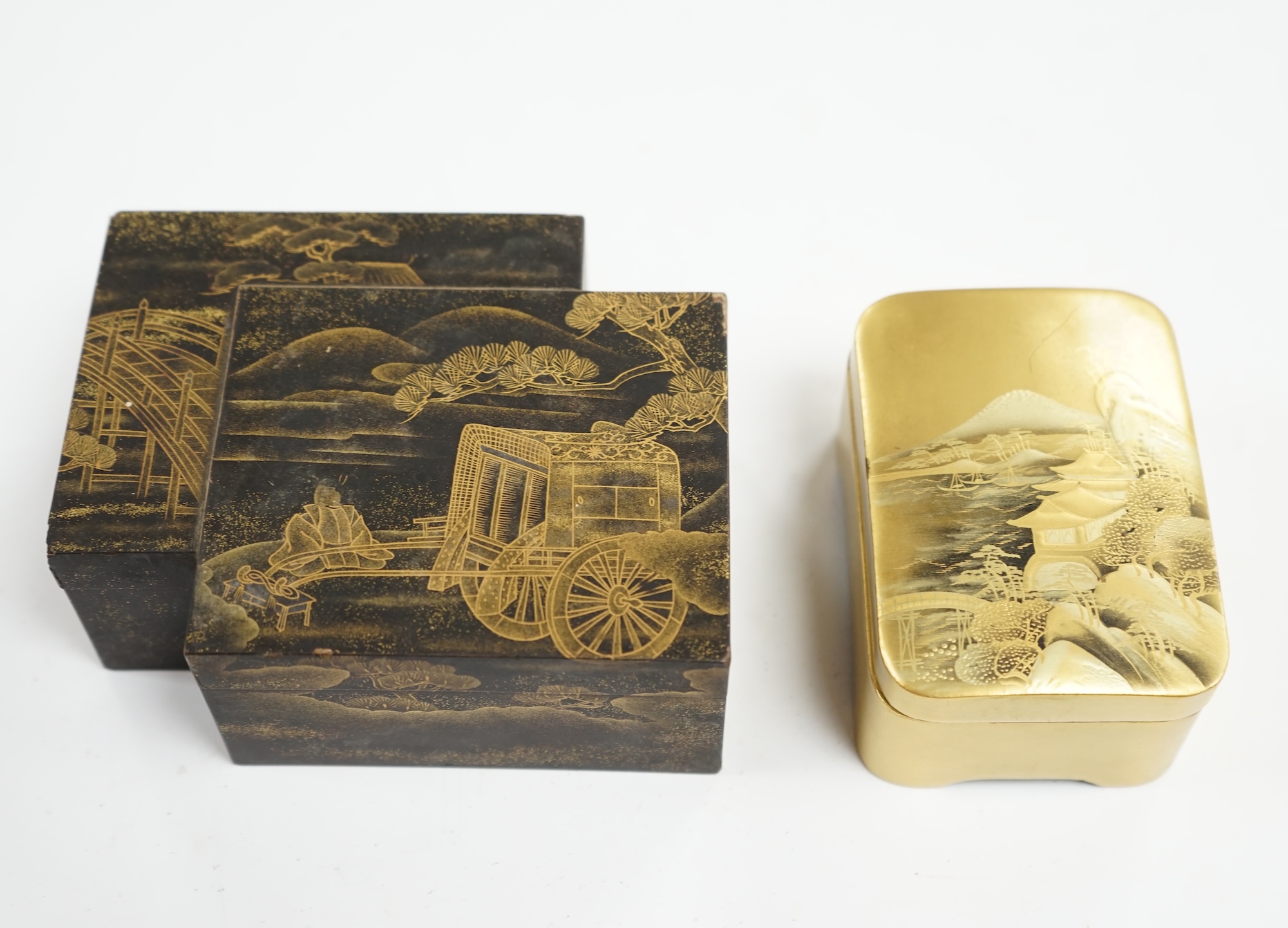 Two Japanese lacquer boxes: one black with gilt decoration, the other gilt with a scene of Mount Fuji etc, largest box 12cm wide. Condition - black and gilt box has some grazes to top edges, gilt box good